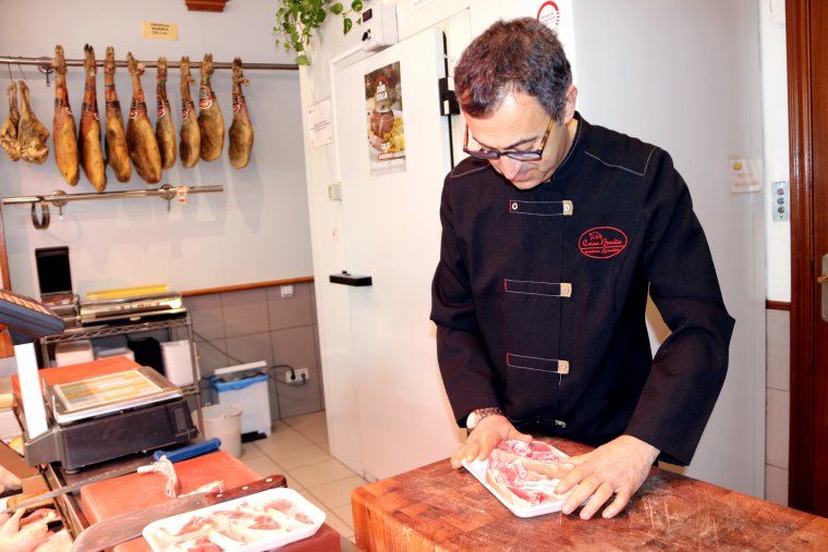 Un carnisser preparant una safata de carn de corder