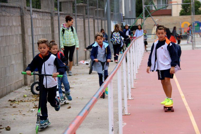 Un grup de nens i nenes arribant a l'escola amb bicicleta i patinet