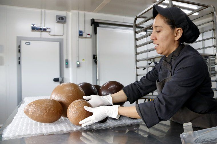 Una de les pastisseres treu els ous de Pasqua de dins dels motlles
